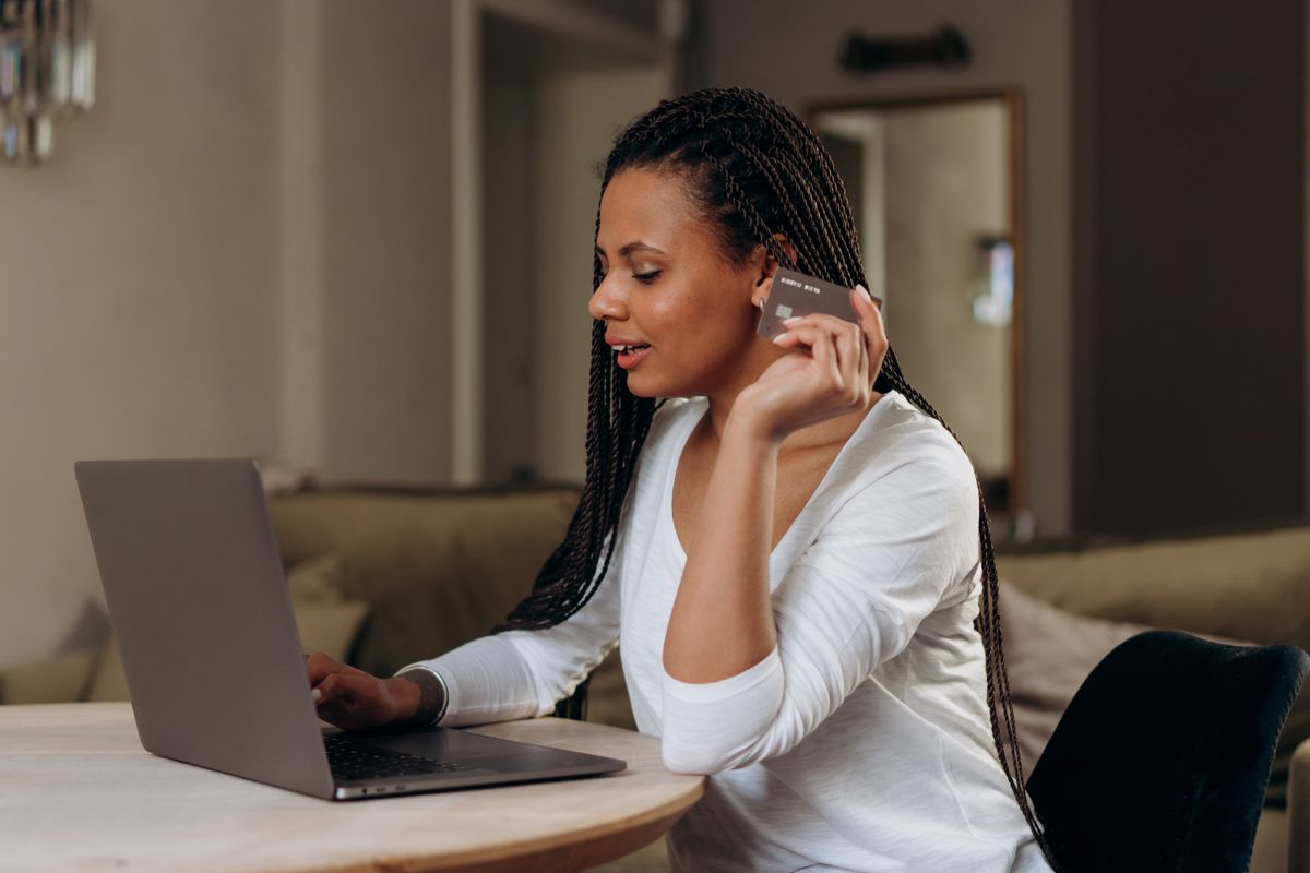 Woman using a laptop with a payment card at home