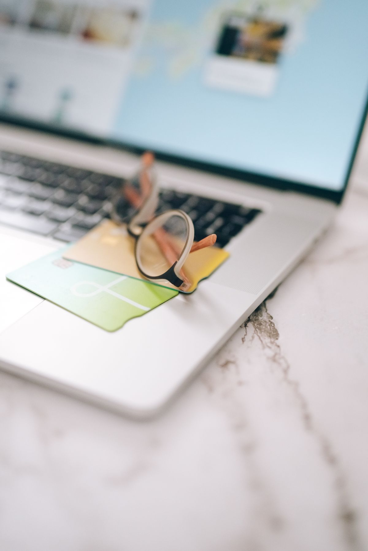 Laptop with glasses and payment cards on a desk